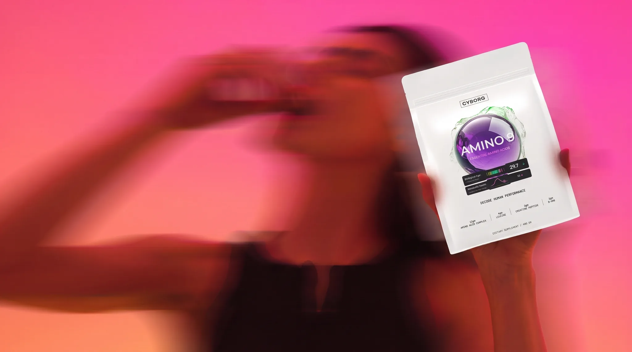 A member holding the CYBORG AMINO 9 pouch, shot in motion against a pink field